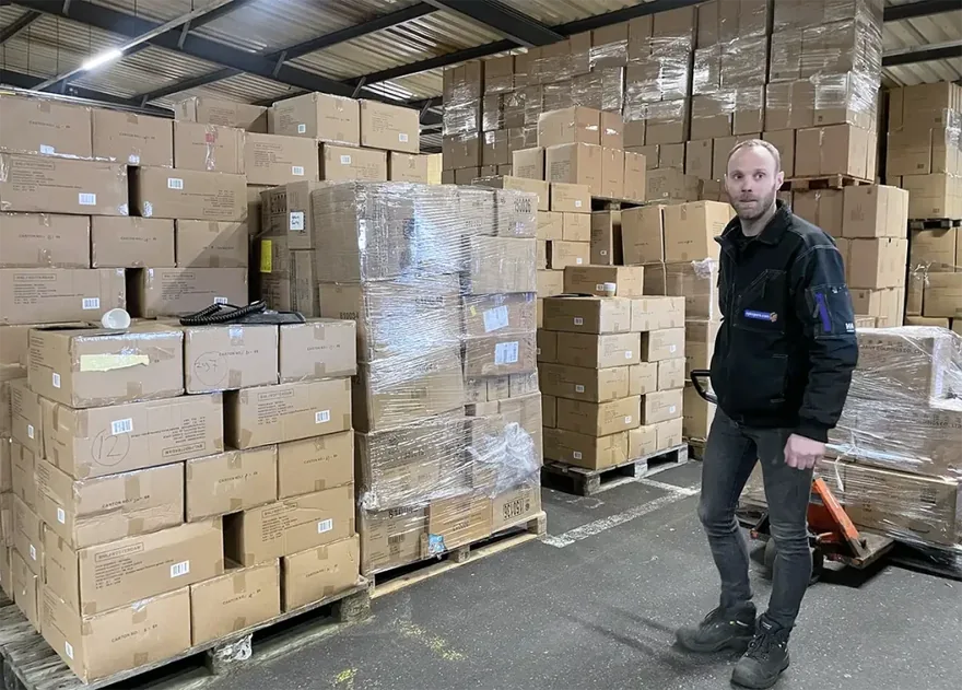 Medewerker van Opkopers.com tussen opgestapelde restpartijen in het magazijn in Leeuwarden